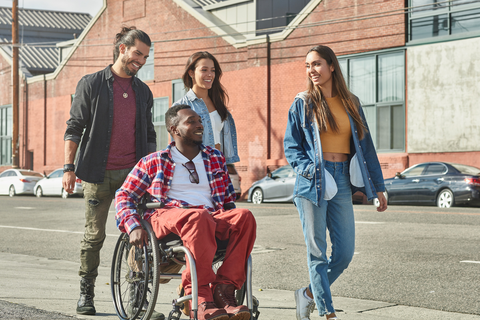 Diverse people walking with disabled man on street